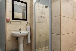 a bathroom with a sink and a shower with a mirror at Ukholo Lodge in Citrusdal