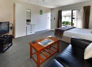 a hotel room with a bed and a coffee table at Classique Lodge Motel in Christchurch