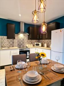 een keuken met een houten tafel met borden en glazen bij Modern and spacious apartment! in Liverpool
