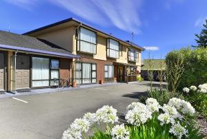 ein Gebäude mit vielen Fenstern und weißen Blumen in der Unterkunft Classique Lodge Motel in Christchurch