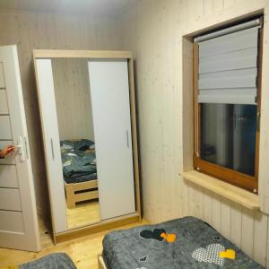 een kamer met een spiegel, een bed en een raam bij Domek całoroczny in Buda Ruska