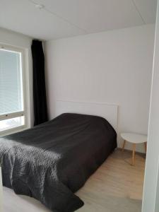 a bedroom with a black bed and a table at Kaksio uudessa talossa in Turku