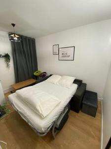 a bedroom with a white bed and a couch at Appartement cosy 10 min stade de France in Saint-Denis