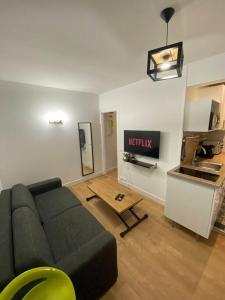 a living room with a couch and a kitchen at Appartement cosy 10 min stade de France in Saint-Denis