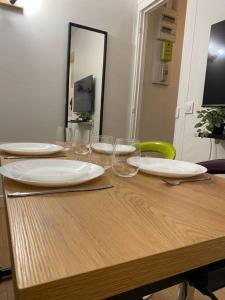 a wooden table with plates and wine glasses on it at Appartement cosy 10 min stade de France in Saint-Denis