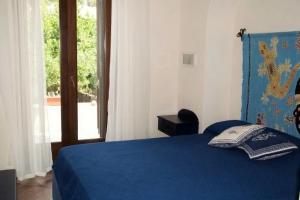 a bedroom with a blue bed and a window at Hiera in Acquacalda