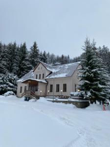 a house in the snow with trees in the background at Penzion Real in Bedřichov
