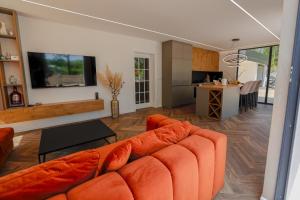 a living room with an orange couch and a kitchen at Villa Diamond One in Banja Luka