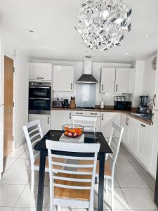 a kitchen with a table and chairs and a chandelier at Private Rooms at Oxley Comfy House - Milton Keynes in Broughton