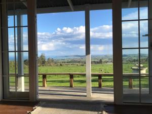 a room with a view of a field through windows at Kereru Cottage in Kaikoura