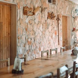 uma parede de pedra com uma mesa e cadeiras de madeira em Masseria La Fiorita em Matera