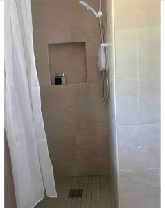 La salle de bains est pourvue d'une douche avec rideau de douche. dans l'établissement 1970s Carratraw Chalet, à Rivory