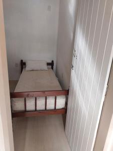 um pequeno quarto com uma cama num quarto em Kitnet Indaiá em Bertioga