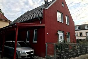 una casa roja con un coche aparcado delante de ella en Urban house for families and Berlin tourists, en Teltow