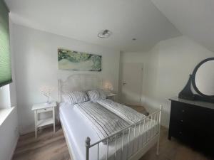 a white bedroom with a bed and a mirror at Urban house for families and Berlin tourists in Teltow