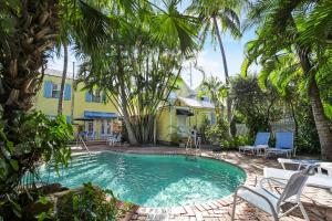 a swimming pool in front of a yellow house with palm trees at Tranquillity Guest House in Key West