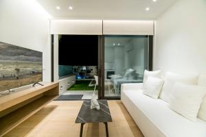 sala de estar con sofá blanco y TV de pantalla plana en GM exclusive Luxury Suites & SPA, en Sitia