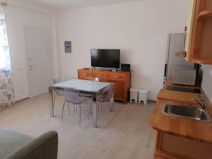une cuisine avec une table et des chaises et une télévision dans l'établissement suite4relax - near poetto beach, à Quartu SantʼElena