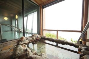 a room with a balcony with rocks and windows at Hotel Tappi in Satogahama