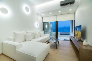 uma sala de estar com um sofá branco e uma televisão em GM exclusive Luxury Suites & SPA em Sitia