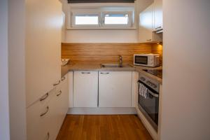 Apartment Central Fulpmes + free parking spot في فولبميس: مطبخ صغير مع دواليب بيضاء وميكرويف
