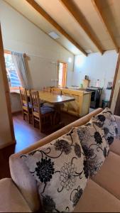 ein Wohnzimmer mit einem Sofa und einem Esstisch in der Unterkunft Cabañas parcela el ciprés in Melipeuco