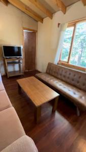 ein Wohnzimmer mit einem Sofa und einem Couchtisch in der Unterkunft Cabañas parcela el ciprés in Melipeuco