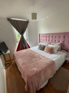 a pink bed with a pink headboard in a bedroom at Departamento Talca , parque seminario in Talca