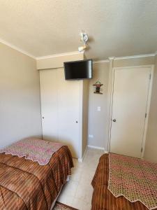 a bedroom with two beds and a flat screen tv on the wall at Departamento Laguna Vista in Algarrobo