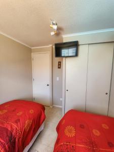 a bedroom with a red bed and a flat screen tv at Departamento Laguna Vista in Algarrobo
