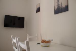a white table with chairs and a tv on a wall at Appartamento Stella in Empoli