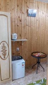 a room with a wooden wall with a table and a stool at Orhidea guest house in Gagra