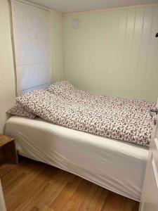 Cama en habitación pequeña con colcha blanca en Gimle Casa en Tromsø