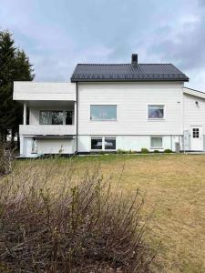 una gran casa blanca con un campo de hierba delante de ella en Gimle Casa en Tromsø