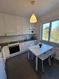 a kitchen with a white table and chairs and a sink at Home Inn SLV4 in Stockholm