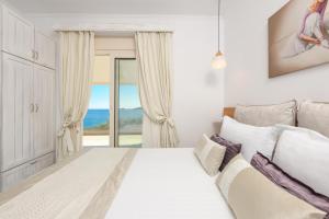 una camera bianca con letto e vista sull'oceano di Villa Niti a Chrisi Ammoudia