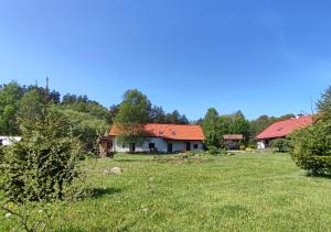 une maison dans un champ planté d'arbres et d'herbe dans l'établissement Ostoja Leśna Cisza, 