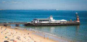 a group of people on a beach near a pier at A&K Inn in Bournemouth