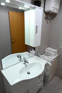 bagno con lavandino bianco e specchio di Residenza Relax dei Trulli ad Alberobello
