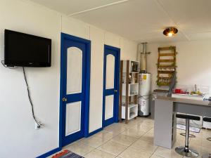 um quarto com portas azuis e uma televisão na parede em Lodging Incógnita, Punta Arenas em Punta Arenas