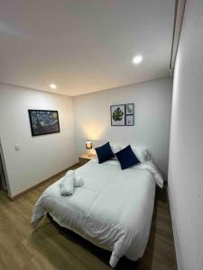 een slaapkamer met een groot wit bed met blauwe kussens bij Aparta-estudio dotado para estrenar in Bogota