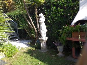 une statue assise dans l'herbe à côté d'un jardin dans l'établissement casa miglio, à Marina di Pietrasanta