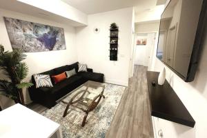 a living room with a black couch and a tv at Exquisite, bright & modern condo. in Niagara Falls