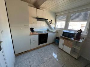 a small kitchen with white cabinets and a sink at Duplex F2 - proche GARE TGV in Mulhouse