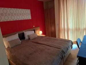 a bedroom with a large bed with a red wall at Apartment Wintermärchen Bansko 4* in Bansko
