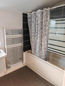 a small bathroom with a shower curtain and a tub at Heads on Bed Pitsea Basildon Essex House with Free Parking Netflix & Wifi in Basildon