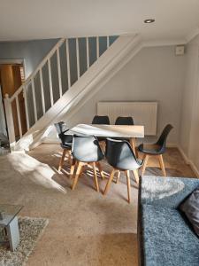 a table and chairs in a room with a staircase at Heads on Bed Pitsea Basildon Essex House with Free Parking Netflix & Wifi in Basildon