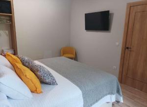 1 dormitorio con 1 cama con almohadas y TV en Los Sauces de la Fuente, en Santillana del Mar