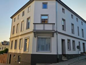 biały budynek z balkonem przy ulicy w obiekcie Apartament na Wodnej w mieście Głogówek