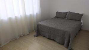 um quarto com uma cama e uma janela com cortinas brancas em Casa no centro de Petrópolis em Petrópolis